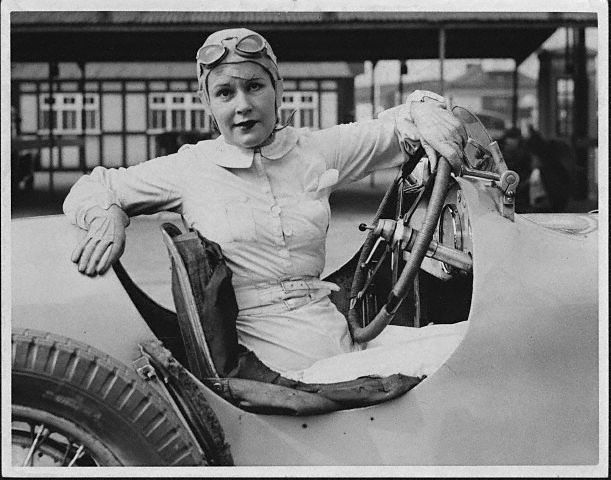 The racing legend, Kay Petre, in her car in the pits at Brooklands, prepares for her first drive since an accident on the circuit, ca. 1938. 